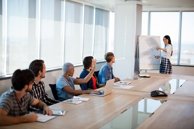 Woman giving presentation to her colleagues in conference room at office