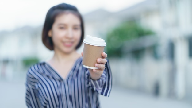 あなたにテイクアウトの紙コップのコーヒーを与える女性。