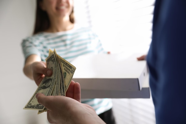 Photo woman giving tips to deliveryman indoors closeup