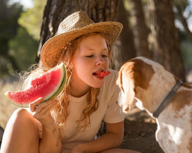 Photo woman giving watermelon to his dog