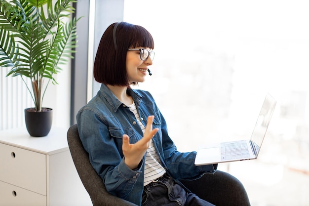 Woman in glasses making video call using laptop webcam