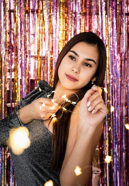 Woman in glitter dress holding christmas lights