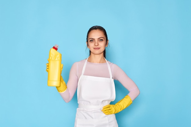 Woman in gloves and cleaner apron holding bottle of detergent