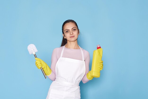 Woman in gloves and cleaner apron holding toilet brush