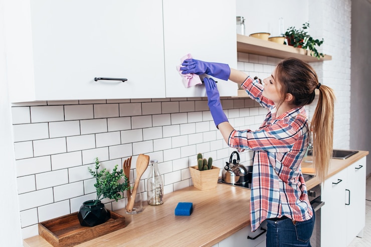 Photo woman in gloves cleaning cabinet with rag at home kitchen.