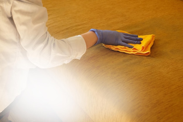 Photo woman in in gloves cleaning sofa with duster at home