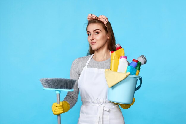 Woman in gloves holding bucket of detergents and broom person