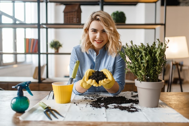 Woman in gloves holds pile of peat for home plants