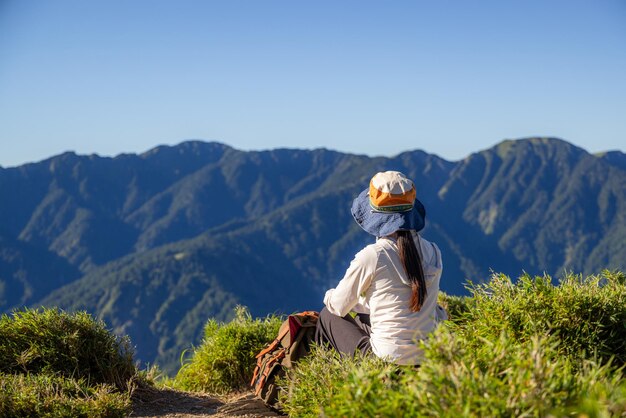 Женщина идет в поход и сидит на вершине смотрит на пейзаж