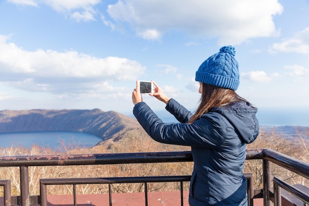 女性はハイキングに行き、携帯電話で写真を撮る