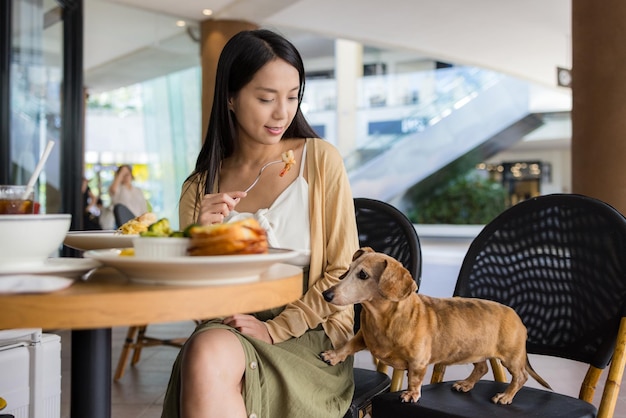 한 여성이 쇼핑 센터에서 개와 함께 레스토랑에 갔다.