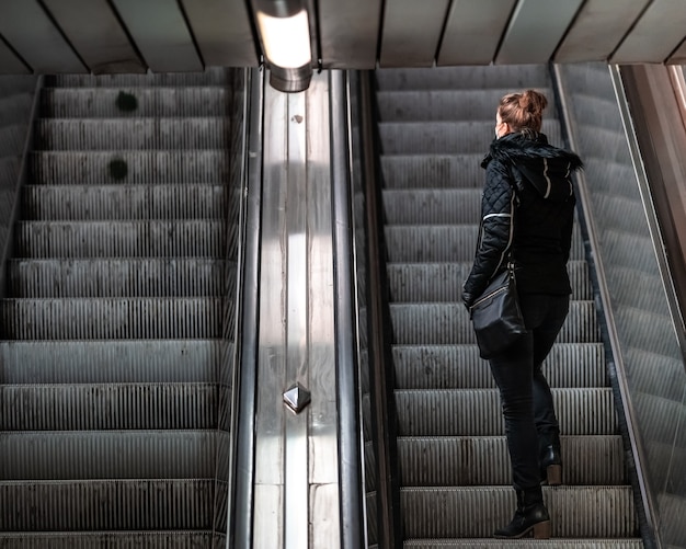 Woman goes on an escalator in the subway