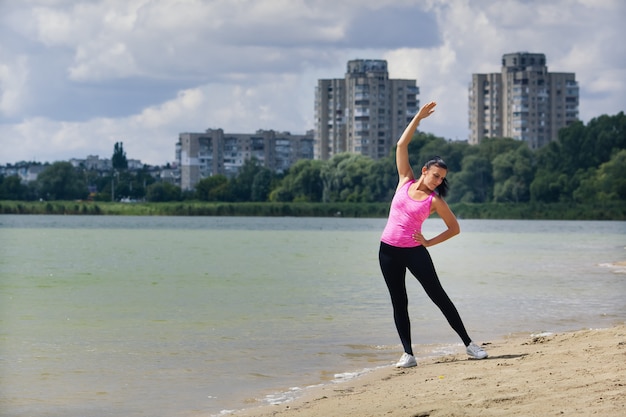 женщина занимается спортом у озера