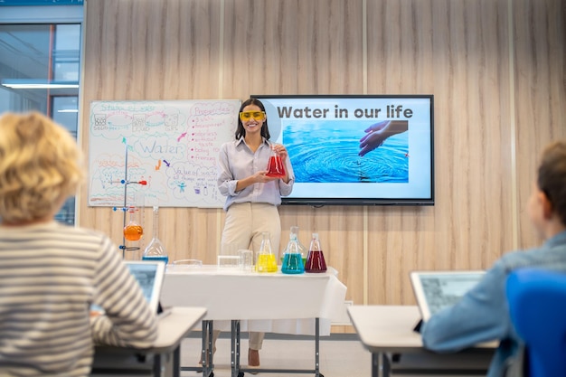 Photo woman in goggles with flask looking at class