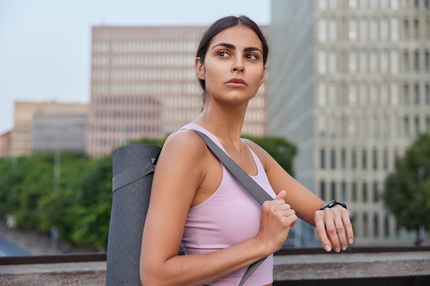 La donna che pratica lo yoga avanzato controlla i risultati dell'allenamento sulle pose dell'orologio fitness in città