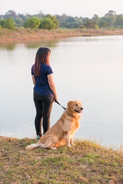 Donna e cane dorato sulla riva del fiume