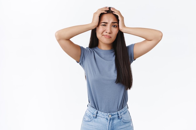 woman grab head head and smirk, squinting puzzled, have doubts and concerns, standing worried