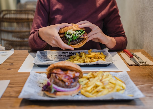 フライドポテトでおいしいハンバーガーをつかむ女性。