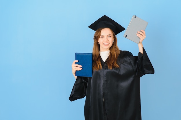 Woman graduate student wearing graduation hat and gown, on blue background