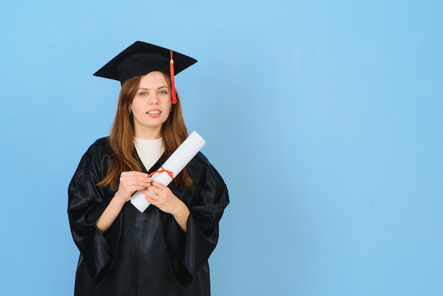 Studente laureato donna che indossa cappello e abito da laurea, su sfondo blu