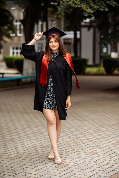 Photo a woman in a graduation cap is wearing a black and red cap