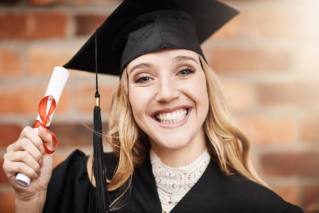 Foto laurea donna e ritratto di uno studente universitario con diploma e sorriso sul viso persona di sesso femminile entusiasta di celebrare il successo dell'istruzione universitaria e il futuro all'aperto all'evento scolastico