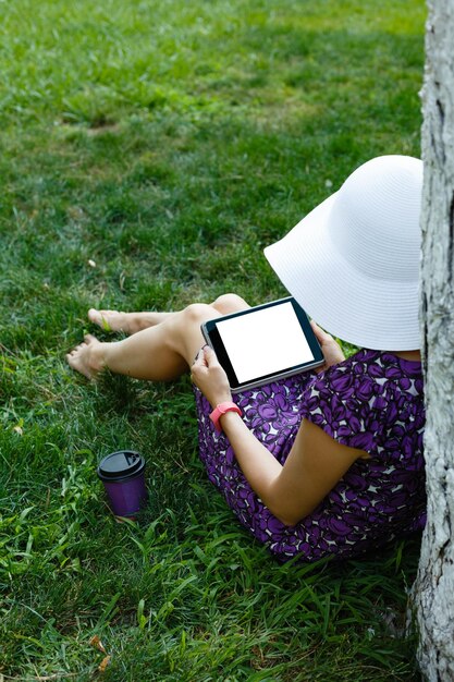 タブレットと草の上の女性