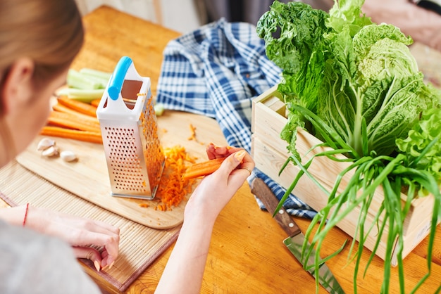 Woman grates the carrots in the kitchen