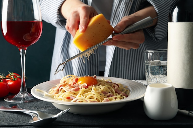 Woman grating cheese on pasta. Cooking pasta composition