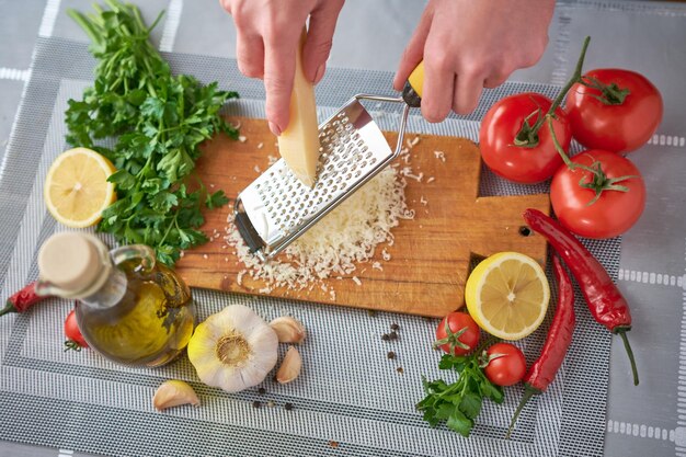 Woman grating parmesan cheese on a grater at domestic kitchen