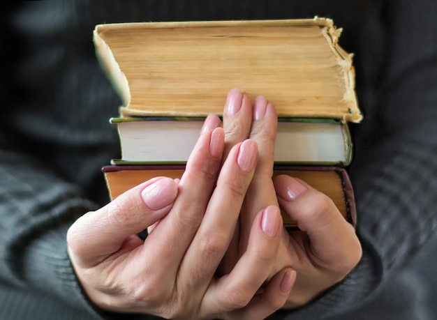 La donna in abiti grigi tiene in mano vecchi libri