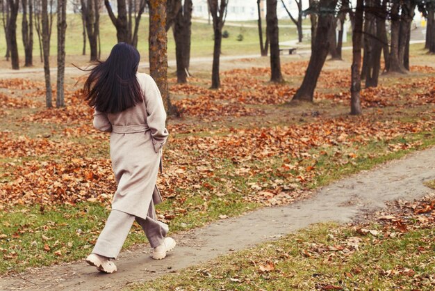 Woman in a gray coat walking in the autumn park