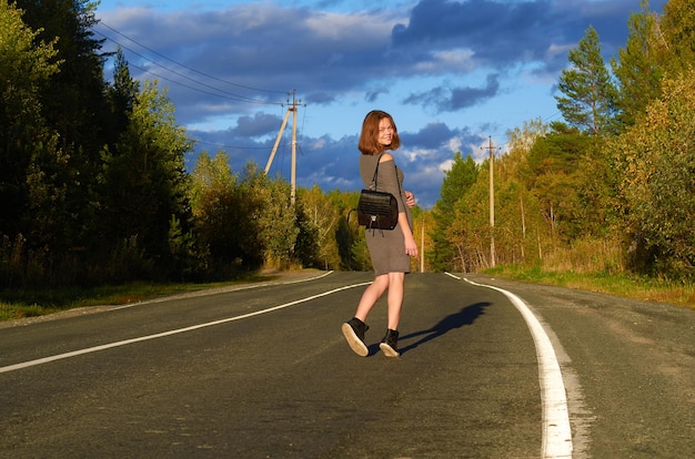 A woman in a gray dress is walking along the road