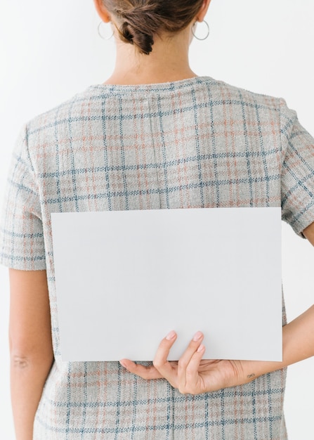 Woman in a gray plaid dress showing a blank card on her back