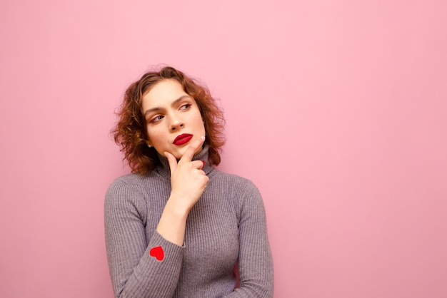 Woman in gray sweater and curly red hair isolated