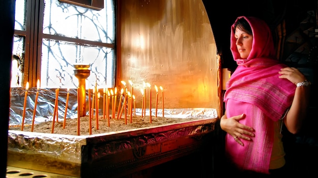 Woman in Greek church looking at burning candles