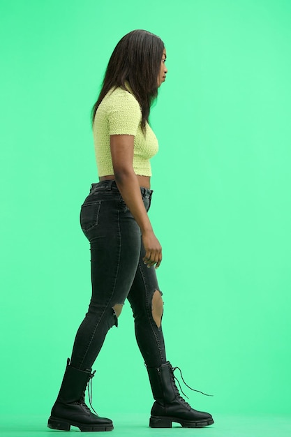 A woman on a green background in full height is walking