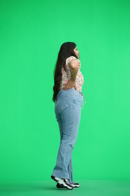 A woman on a green background fulllength waiting in profile