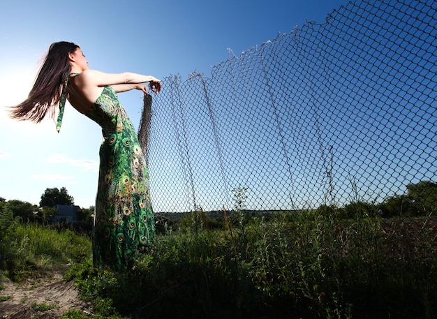 Женщина в зеленом платье на открытом воздухе и голубое небо