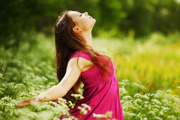 緑の芝生のフィールドの女性は自由を感じる