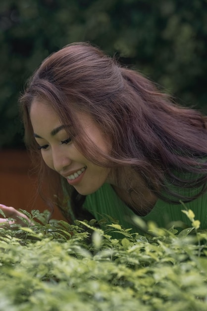 A woman in a green shirt is looking at a plant