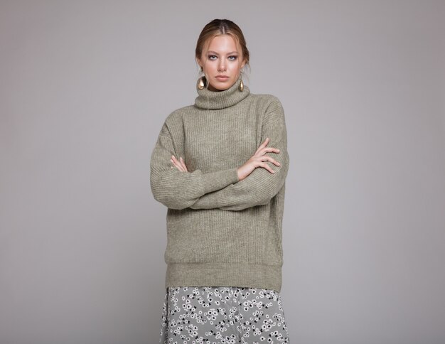 Woman in green sweater long skirt patterns on gray background Studio shot Monochrome colors