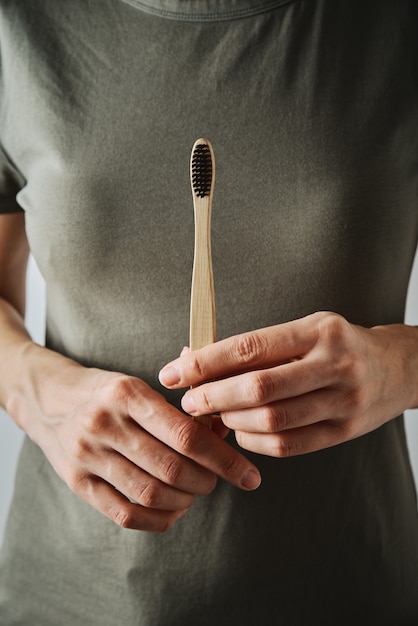 Woman in green t-short holds bamboo toothbrush