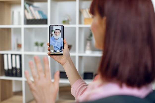 Foto donna che saluta il nonno durante la videochiamata sullo smartphone