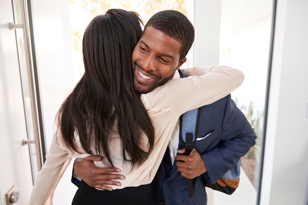 Женщина приветствует и обнимает мужа бизнесмена, когда он возвращается домой с работы
