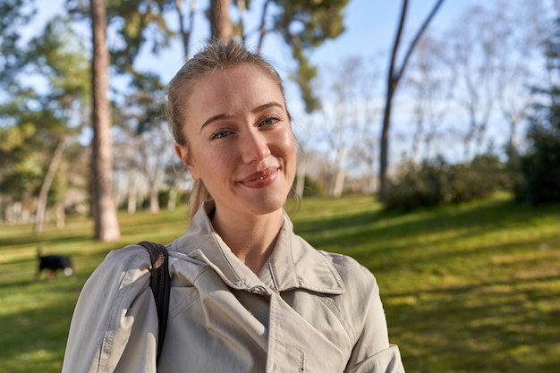 A woman in a grey coat smiles at the camera.