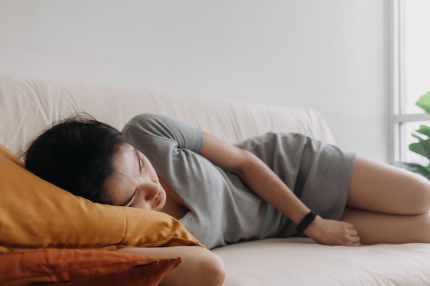 Woman in grey dress is sleeping and relaxed on the sofa in the apartment