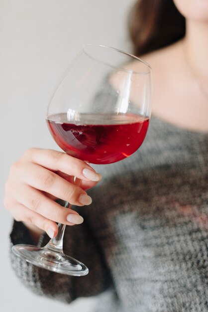 Woman in a grey sweater with a glass of red wine