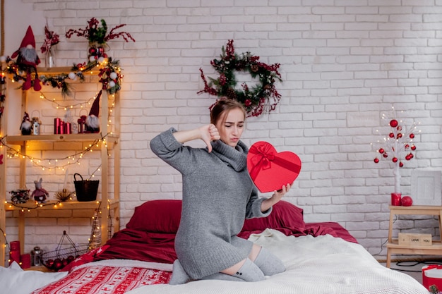 Photo woman in a grey sweater with a red gift box