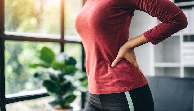 woman grimaces in pain clutching lower back symbolizing discomfort and health issues